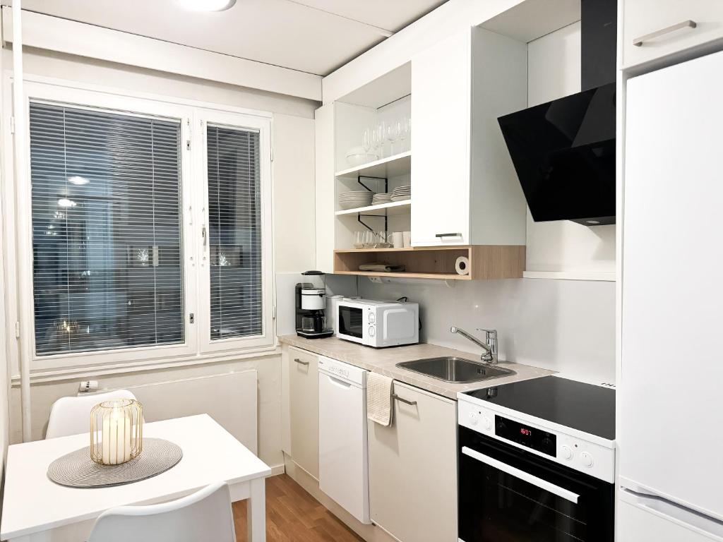 a white kitchen with a sink and a microwave at Aurora City Studio By BookLapland in Rovaniemi