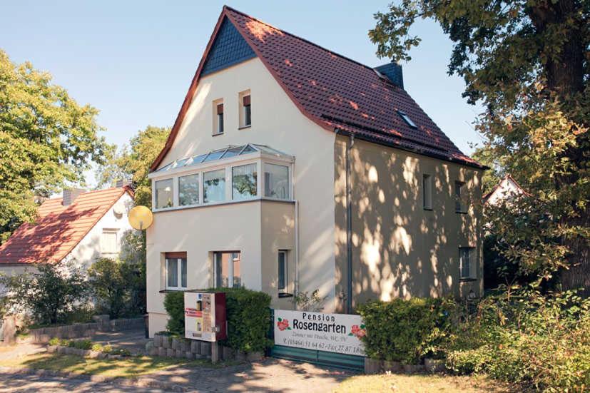 una gran casa blanca con techo rojo en Pension Rosengarten, en Sangerhausen