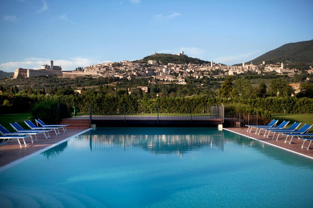 a large swimming pool with chairs and a city at Hotel Bellavista in Assisi