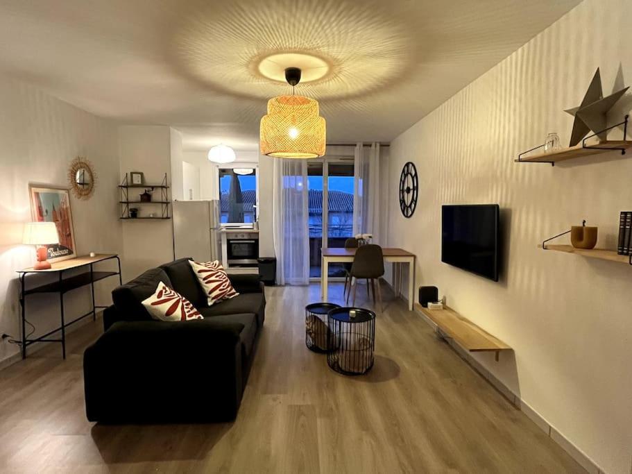 uma sala de estar com um sofá e uma mesa em Le lac du pigeonnier em Colomiers