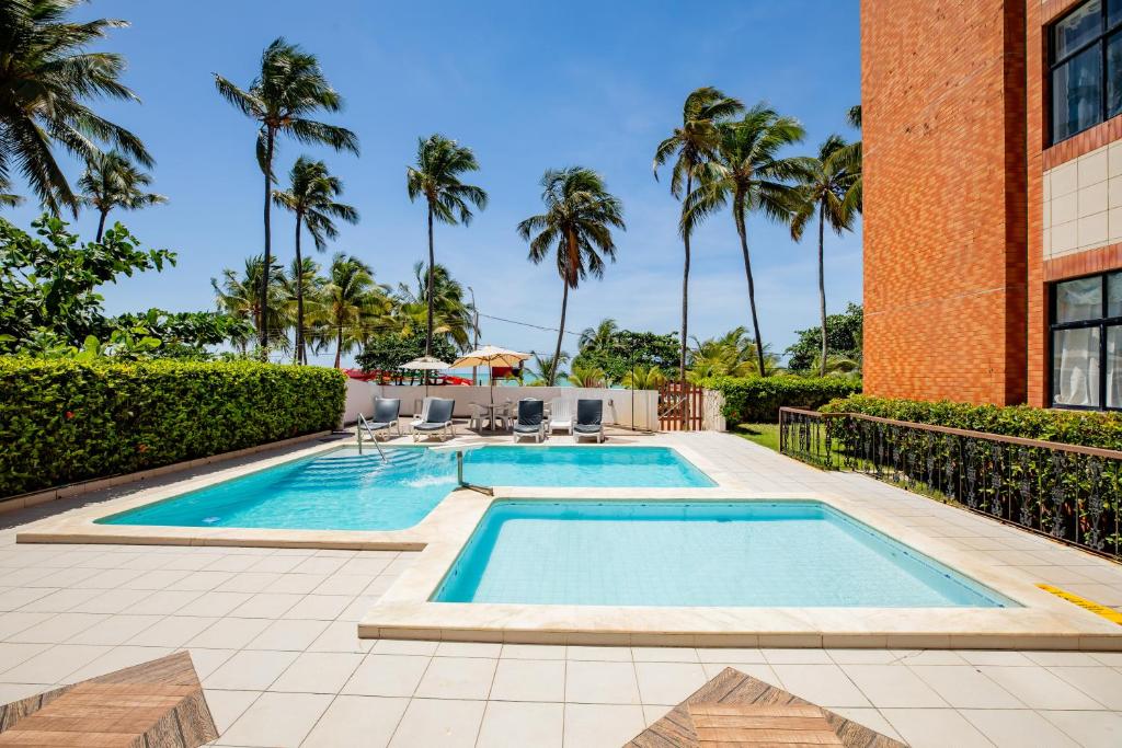 馬塞約的住宿－Moriah Maceió Beach Hotel，一座棕榈树游泳池和一座建筑