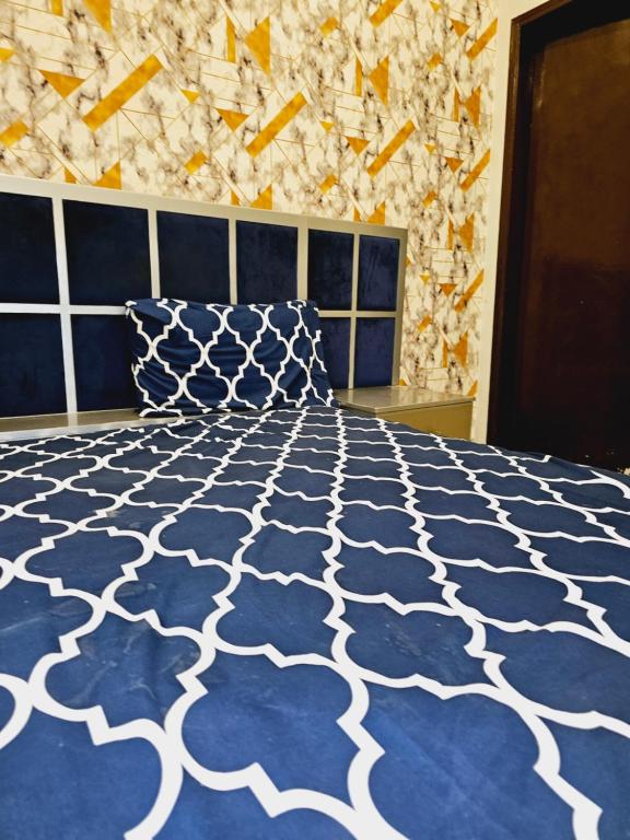 een slaapkamer met een blauw en wit bed en een stenen muur bij Rose Palace Hotel Karachi in Karachi