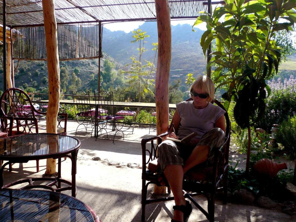 a woman sitting in a chair on a patio at Auberge Tigmmi N'Tamazirte in Ijjoukak