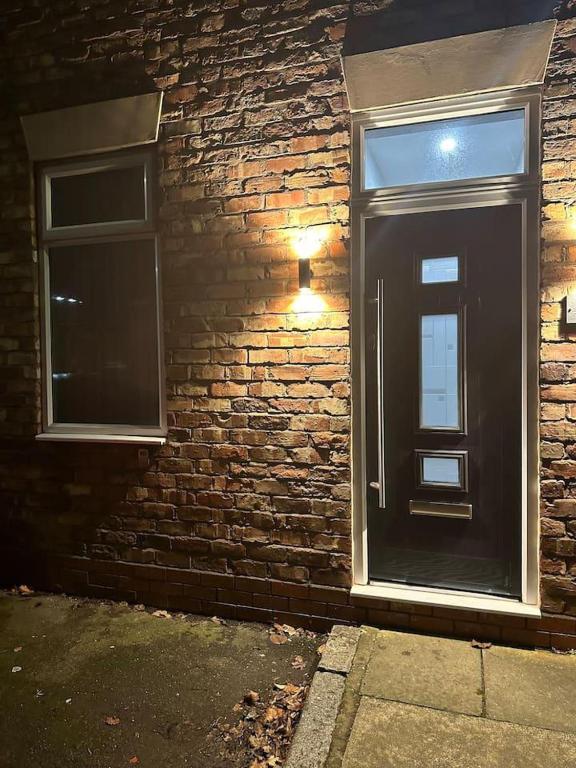 a black door on the side of a brick building at Immaculate 4-Bed detached House in Bootle in Bootle