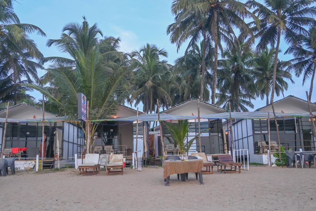 a building on the beach with chairs and palm trees at Kashinath Beach Huts in Agonda