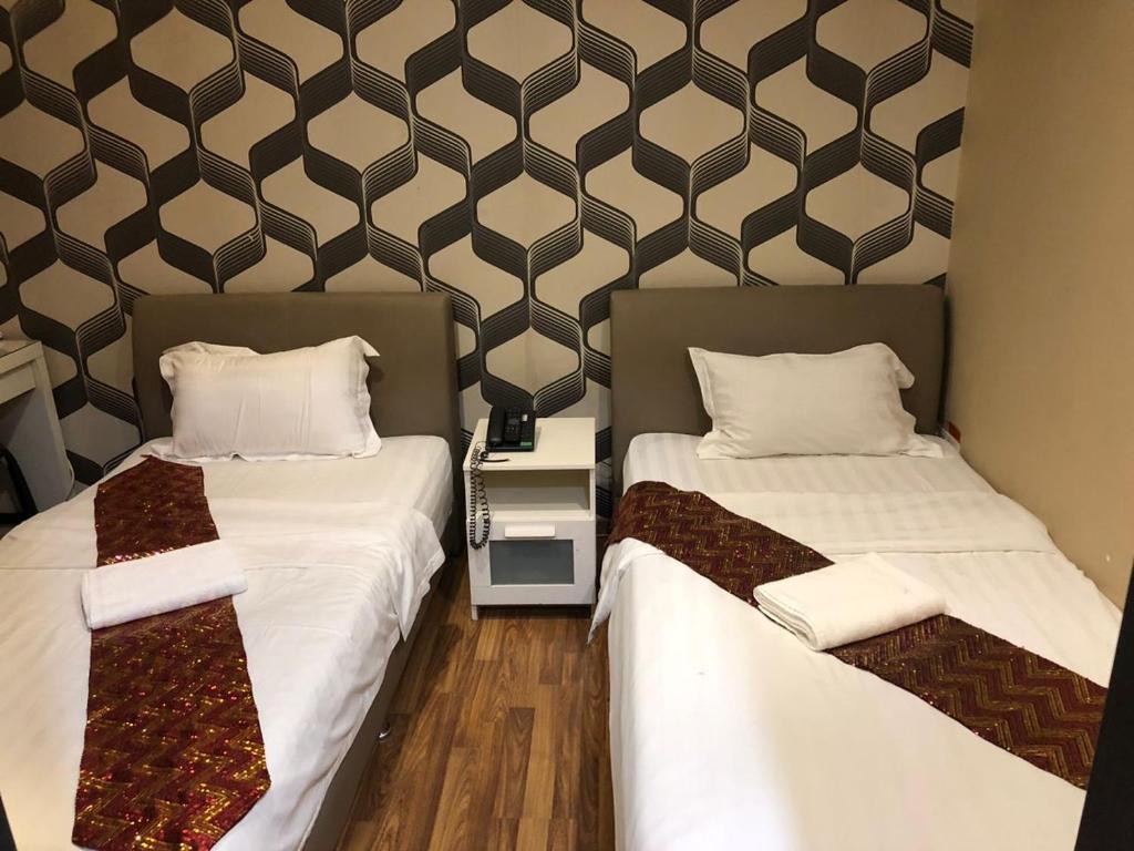 2 Betten nebeneinander in einem Zimmer in der Unterkunft M BOUTIQUE INN (BINTANG JAYA) in Miri