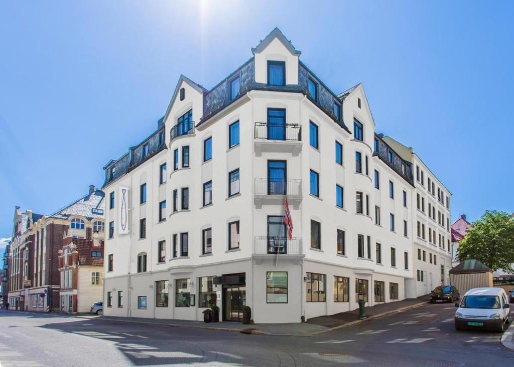 een wit gebouw met blauwe ramen op een straat bij Heimen Hotel in Bergen