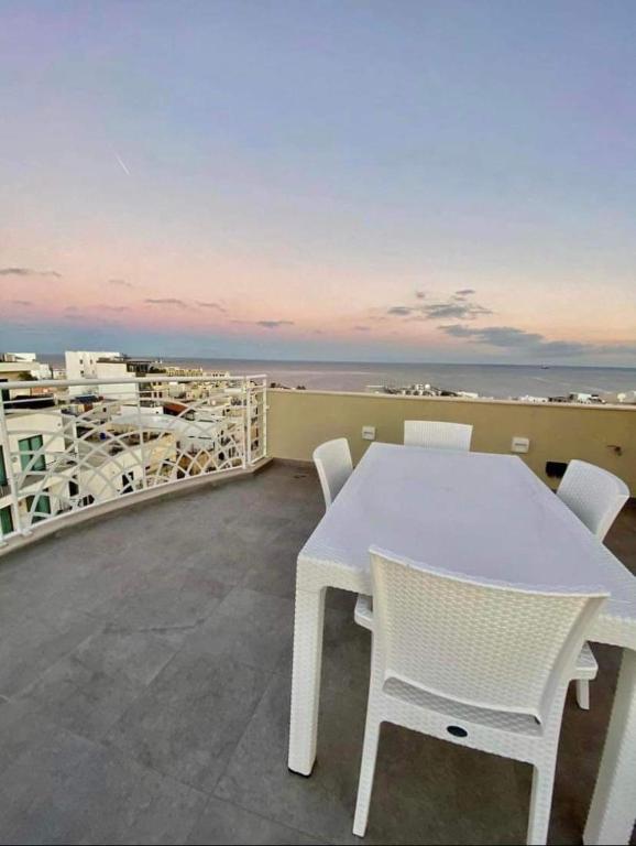 einen weißen Tisch und Stühle auf einem Balkon mit Meerblick in der Unterkunft Marsaskala 1 bedroom penthouse in Marsaskala