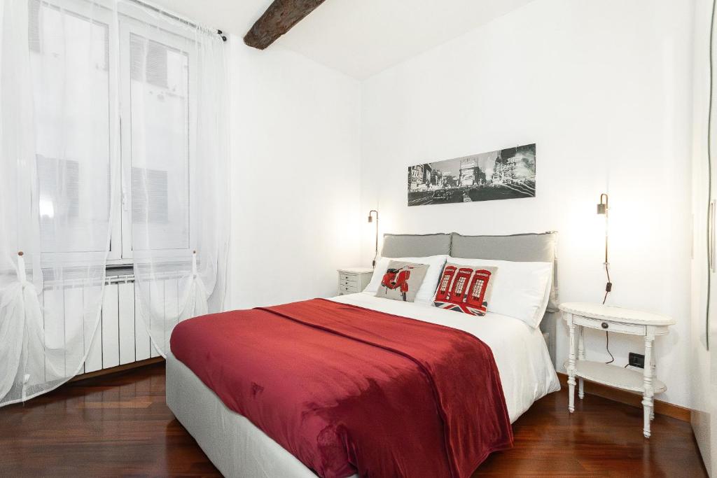 um quarto branco com uma cama grande e um cobertor vermelho em CENTRO CITTÀ - ACQUARIO di Genova em Gênova