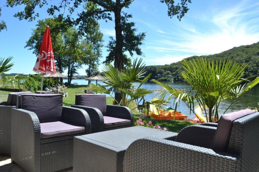 a group of wicker chairs and tables next to a lake at Camping les Cantarelles in Alrance