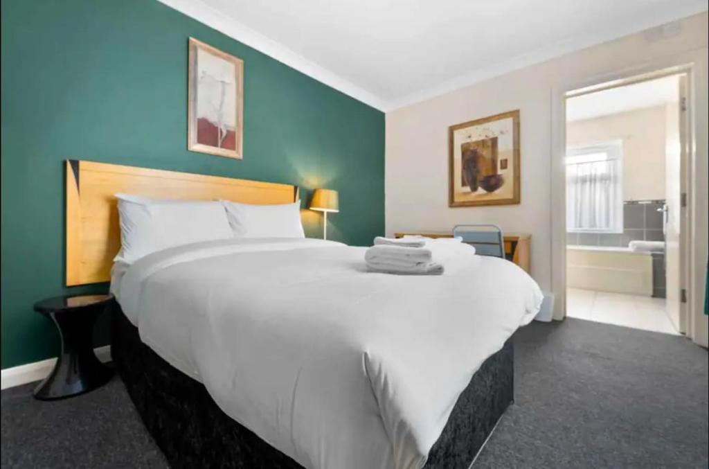 カーディフにあるEnsuite Room in Cardiff City Centreのバスルーム付きの客室で、白い大型ベッド1台を利用できます。