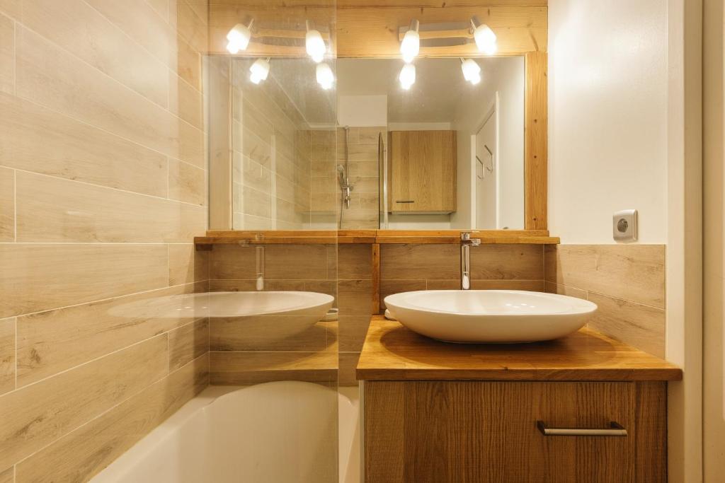 a bathroom with two sinks and a mirror and a tub at Chamonix Sud - Forclaz 304 - Happy Rentals in Chamonix
