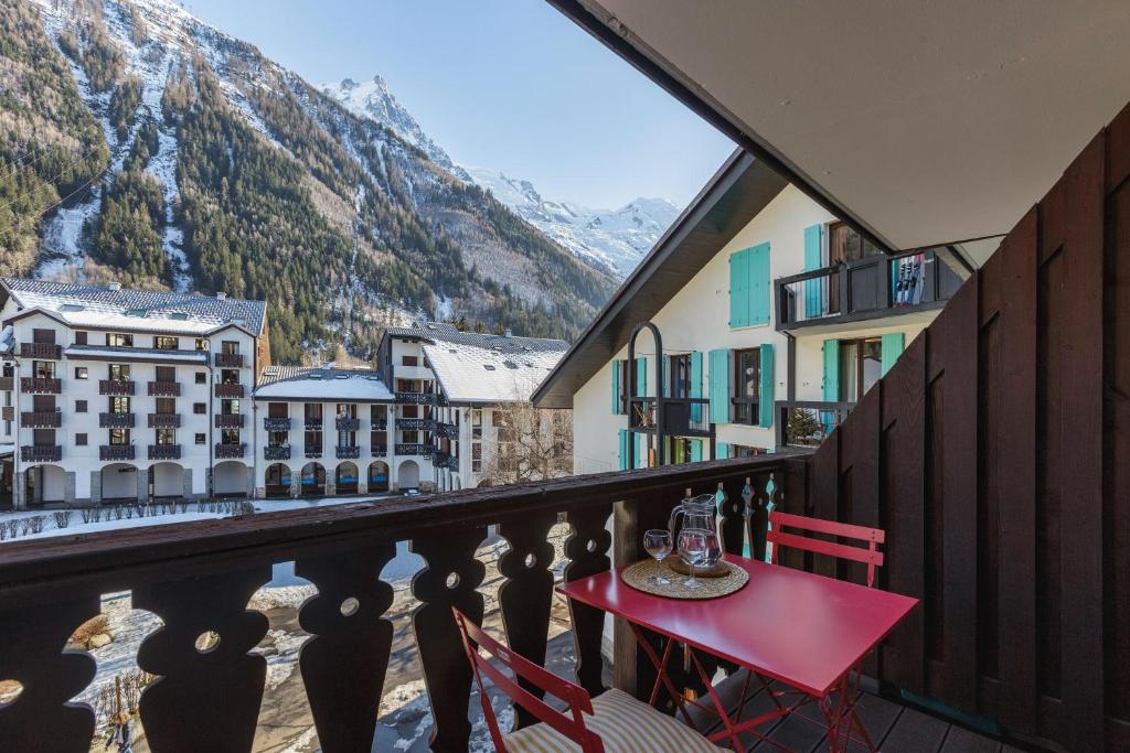 a red table and chairs on a balcony with mountains at Chamonix Sud - Forclaz 304 - Happy Rentals in Chamonix