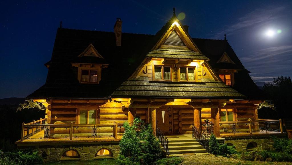 a large wooden house with a moon in the sky at Dom pod Smokami in Bukowina Tatrzańska