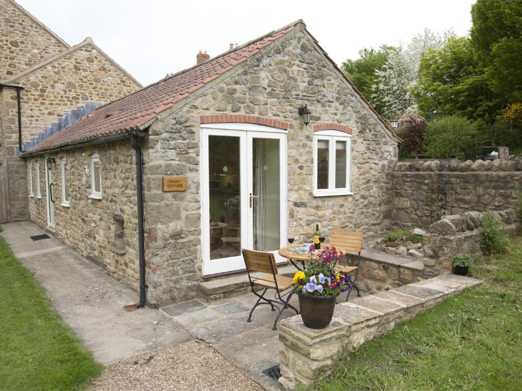 a small stone house with a table and a chair at 1 bed in Bedale G0094 in Crakehall