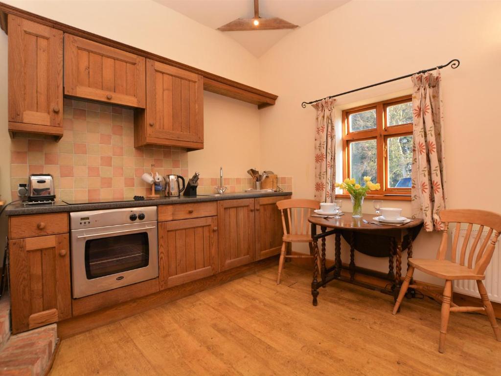 a kitchen with wooden cabinets and a table and a window at 1 Bed in Lincoln 73852 in East Barkwith