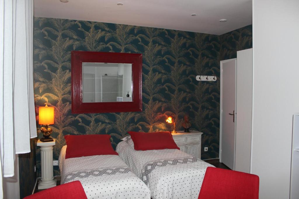 a bedroom with two beds with red pillows and a mirror at PARIS de FLORE Stane in Malakoff