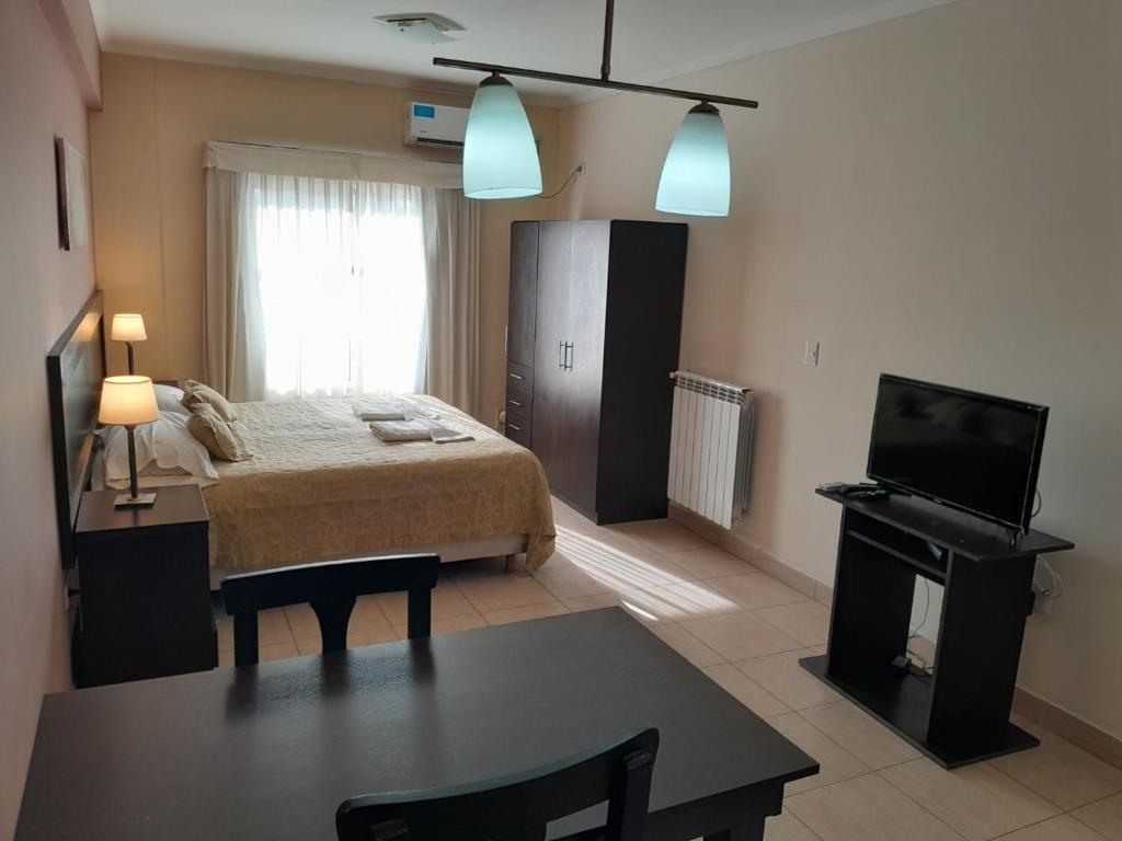 1 dormitorio con cama, mesa y TV en Antares Apartments en Campana