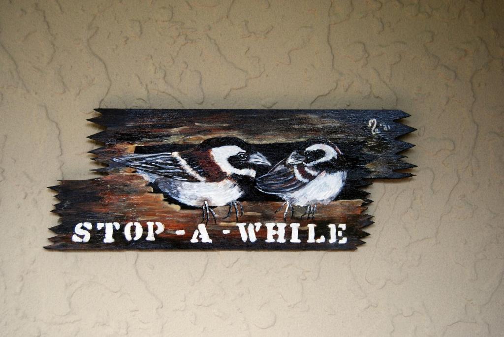 a sign with two birds on it hanging on a wall at Stop-a-While in Krugersdorp