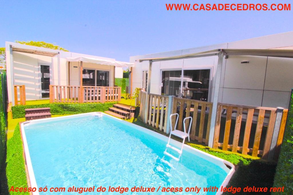 a swimming pool in a yard next to a house at Lodges de cedros in Setúbal