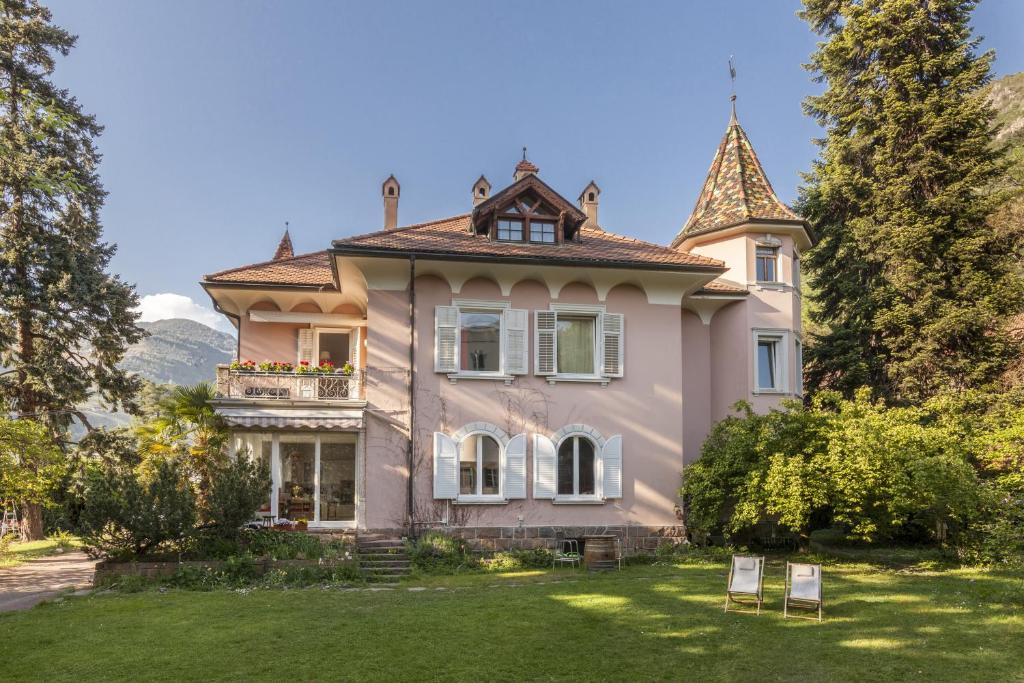 a large pink house with a tower at Apartments Villa Anita in Bolzano