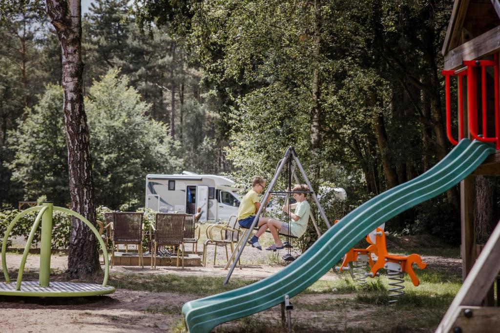dos personas sentadas en un columpio en un patio de juegos en Camping Siësta, en Lille