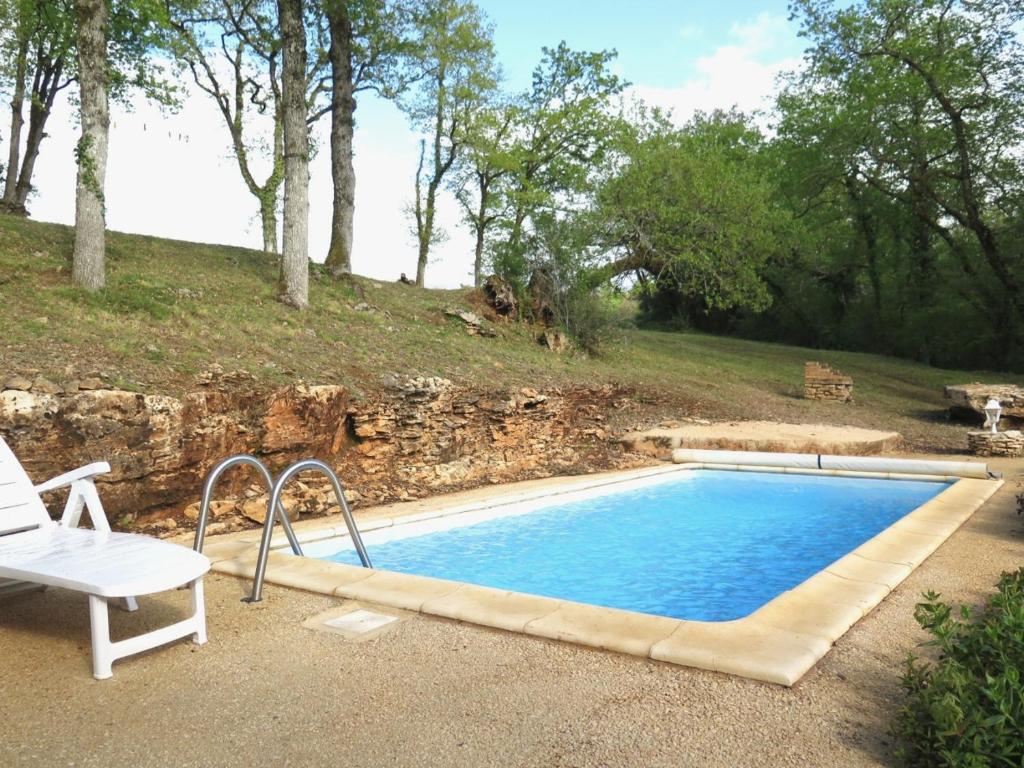 una piscina con una silla blanca al lado en Domaine Le Mayne - Le Châtaignier - Clévacances 2 Clés, en Blanquefort-sur-Briolance
