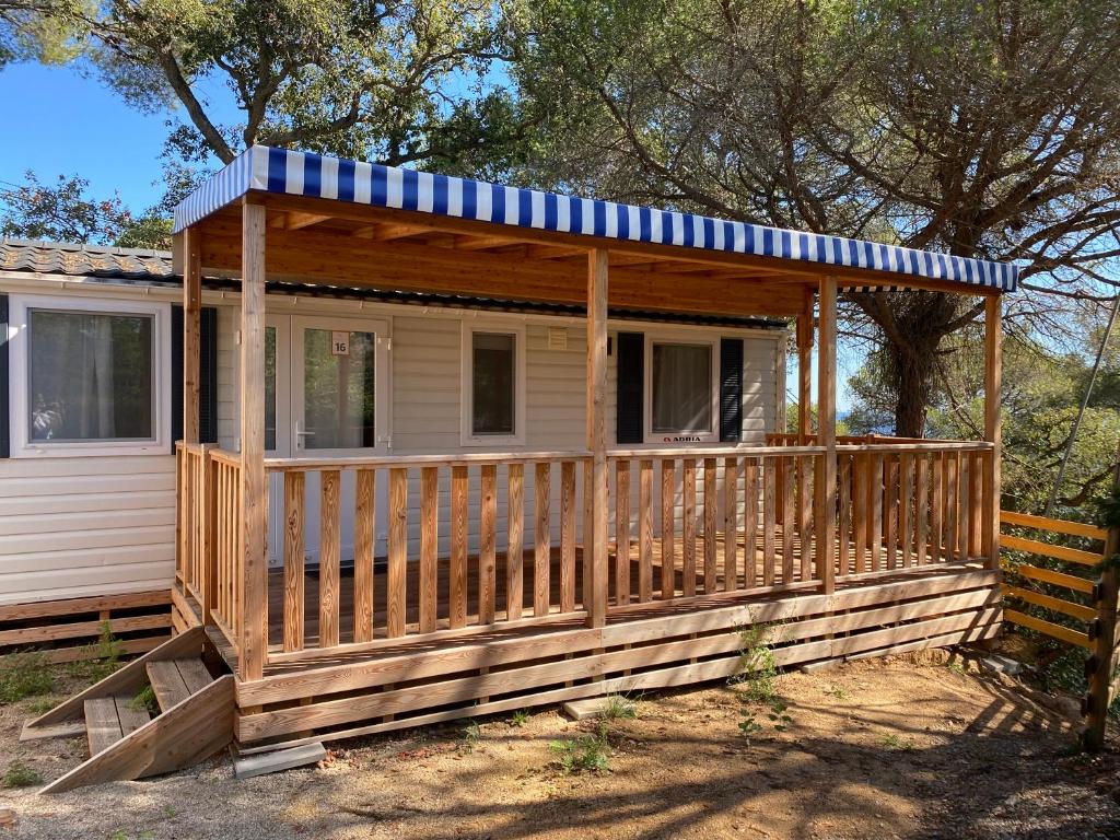 eine Holzhütte mit einer Veranda und einem blauen und weißen Dach in der Unterkunft Albatross Mobile Homes on Camping Cala Canyelles in Lloret de Mar