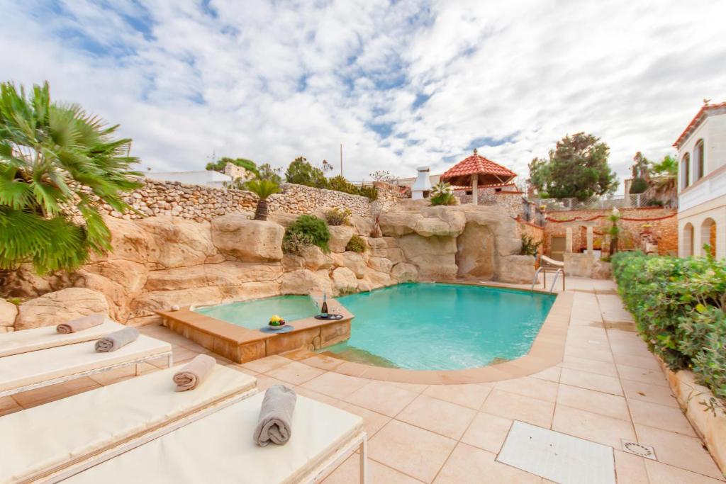 een zwembad in een achtertuin met een rotswand bij Villa & Pool Apartments in Mellieha Bay - Happy Rentals in Mellieħa