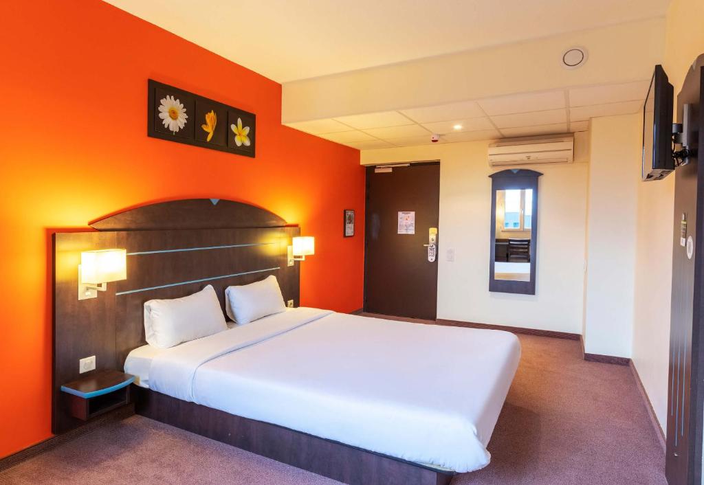 カステルキュリエにあるB&B HOTEL Agen Castelculierのベッドルーム1室(オレンジ色の壁の大型ベッド1台付)