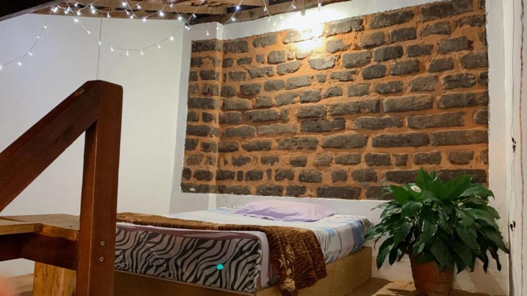 a bedroom with a brick wall and a bed at Hostel Paraguassú in Mucugê