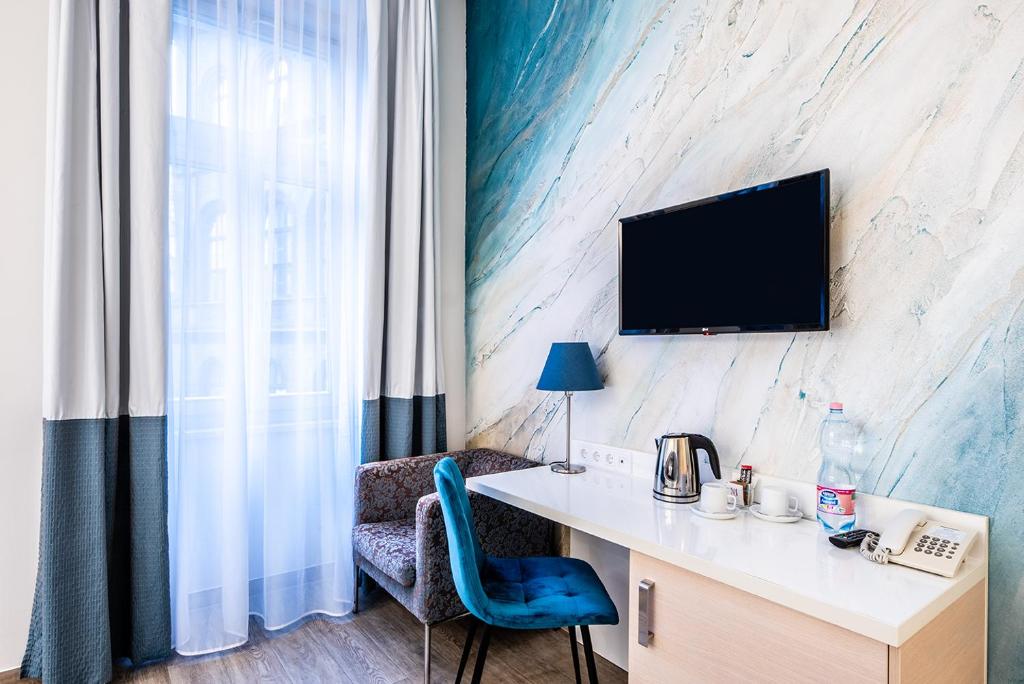 Habitación con escritorio y TV en la pared. en Atrium Fashion Hotel, en Budapest
