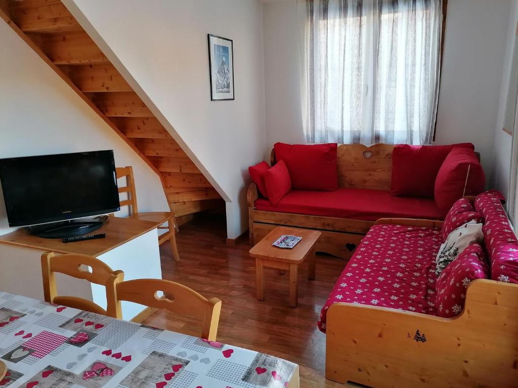 salon z czerwoną kanapą i telewizorem w obiekcie Charmant Chalet Duplex 6 Pers, Résidence 3* avec Piscine, Superdevoluy, à 300m des Pistes - FR-1-504-634 w mieście Superdevoluy