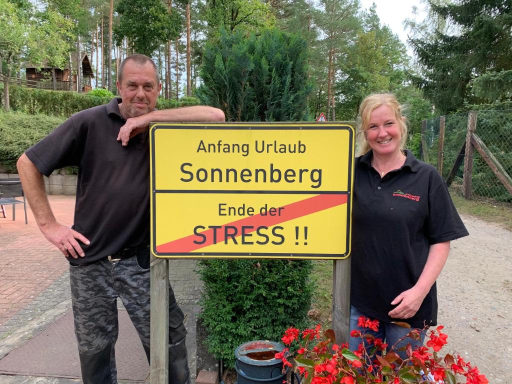 Ein Mann und eine Frau stehen neben einem Schild in der Unterkunft Camping Sonnenberg in Faßberg