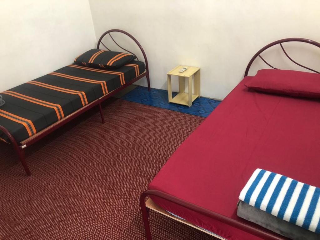 um quarto com duas camas e uma pequena mesa em Easah Homestay Malacca em Malaca