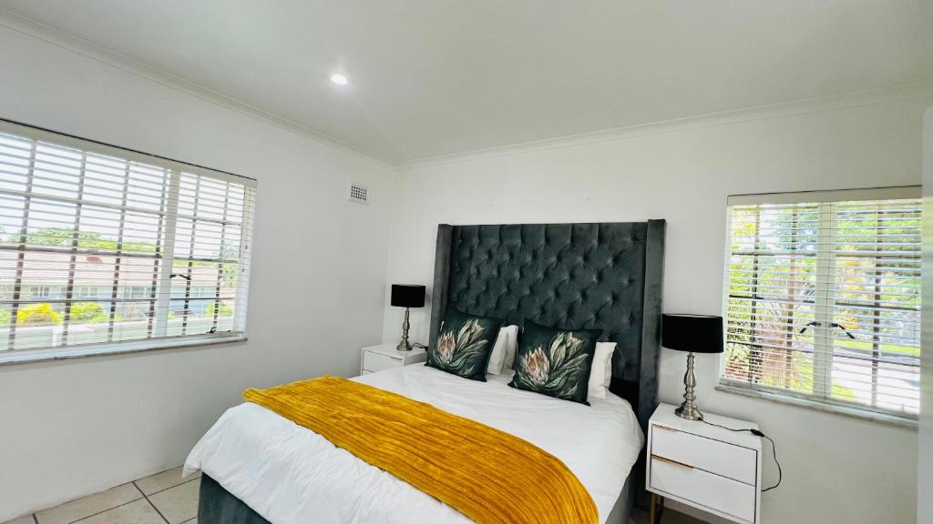 a bedroom with a large bed and two windows at Casablanca Guest House in Durban