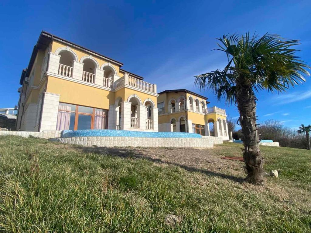 a yellow house with a palm tree in front of it at VILLAS GOLF in Balchik