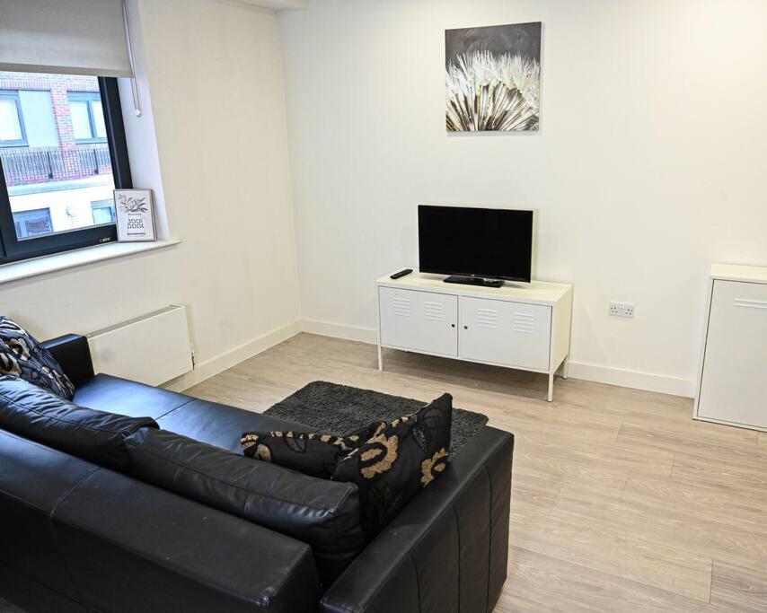 a living room with a black leather couch and a tv at Chic 1 Bedroom Flat in Bedford