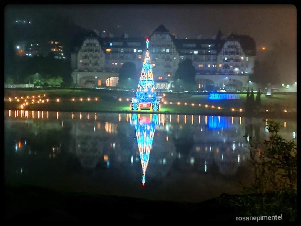 Un árbol de Navidad reflejándose en el agua por la noche en Loft particular - Palácio Quitandinha, en Petrópolis