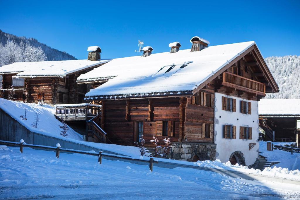 a wooden house with snow on the roof at Les Chalets PVG in La Clusaz