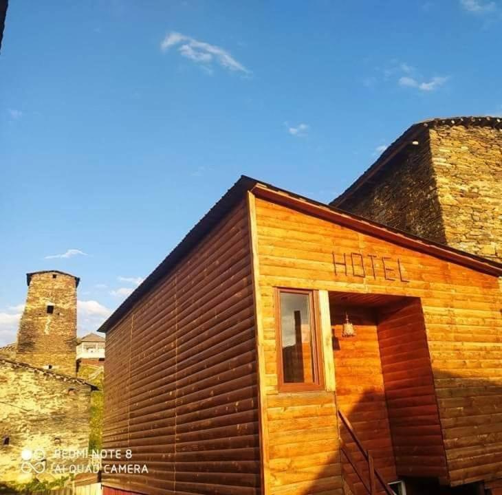 un pequeño edificio de madera con un castillo en el fondo en Guesthouse Luka, en Ushguli