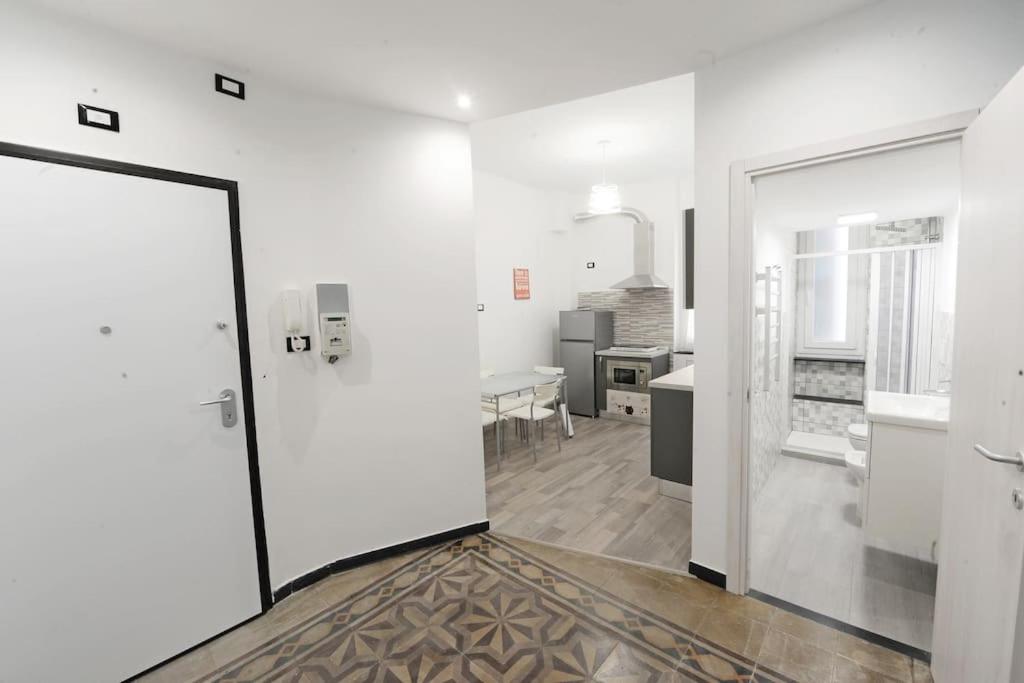 a white room with a door and a kitchen at Lauretta: Appartamento adiacente metro in Genoa