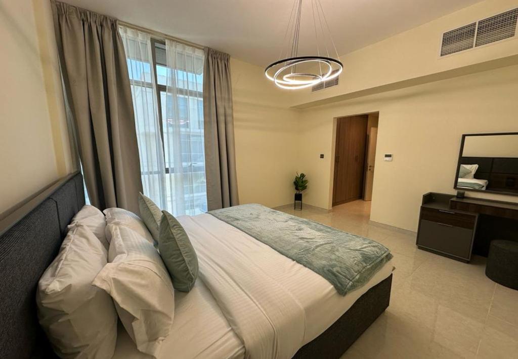 a bedroom with a large bed and a desk in it at EasyGo - Polo Residence 1 Bedroom Community View in Dubai