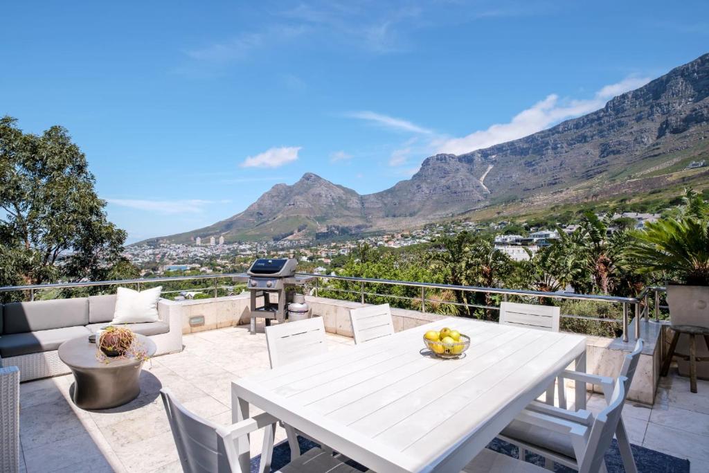 a white table and chairs on a balcony with mountains at Table Mountain Views in Cape Town