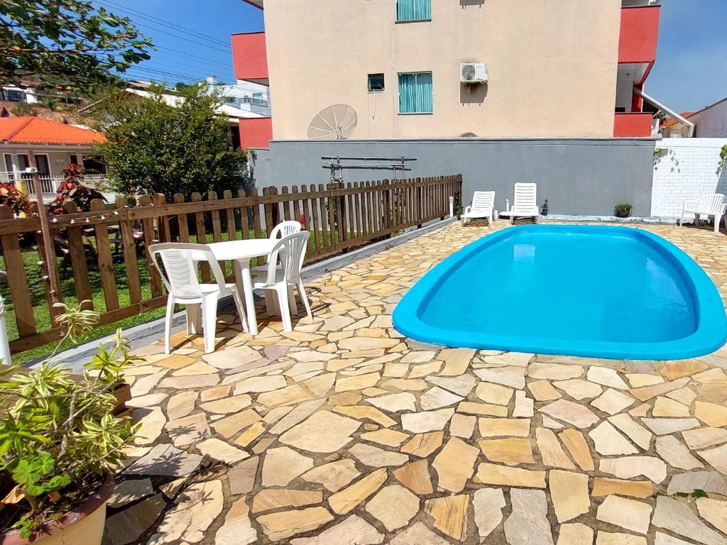 a blue swimming pool with a table and chairs at Residencial Bem Estar in Bombinhas