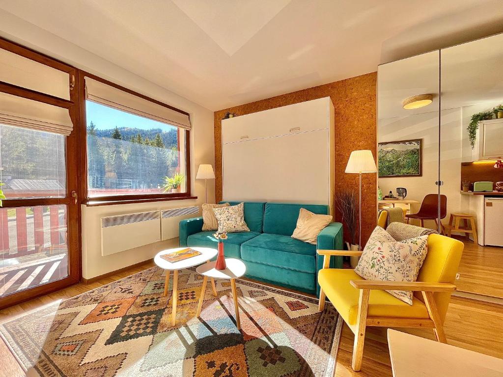 een woonkamer met een blauwe bank en twee stoelen bij Sunny studio close to the slopes in Borovets