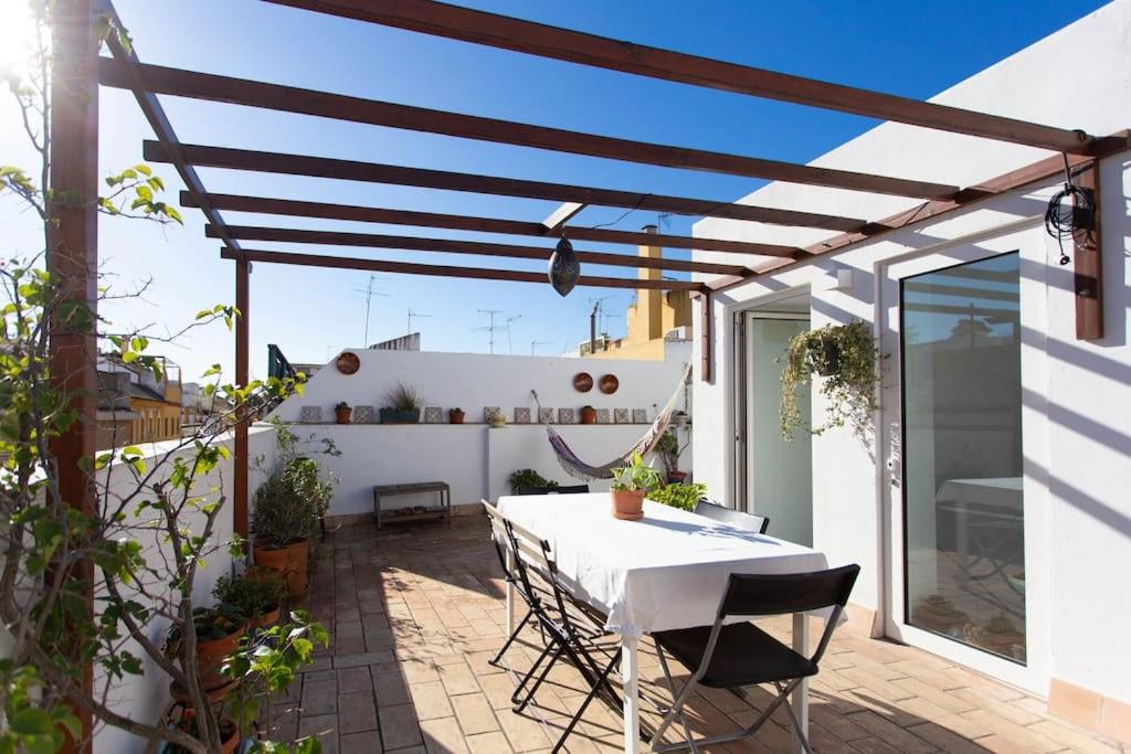 un patio con una mesa blanca y sillas en Town house with rooftop terrace en Sevilla