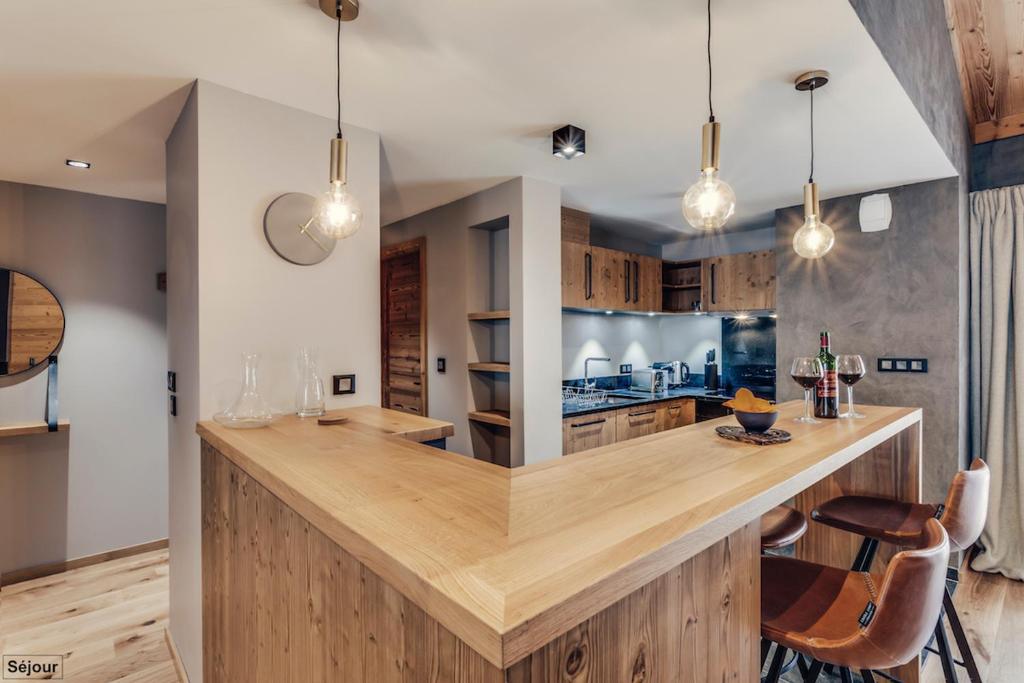 a kitchen with a large wooden counter with chairs at Hôtel Avancher in Val-d'Isère