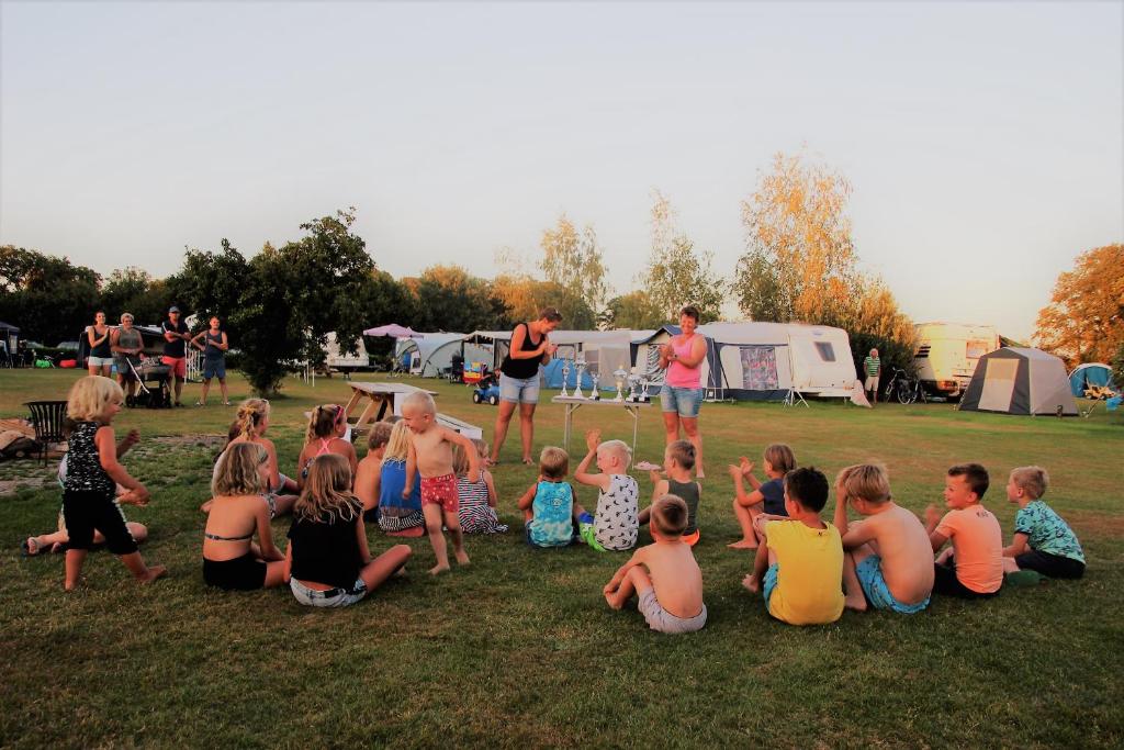 eine Gruppe von Kindern, die auf dem Rasen auf einem Feld sitzen in der Unterkunft Minicamping Falkenborg in Beltrum