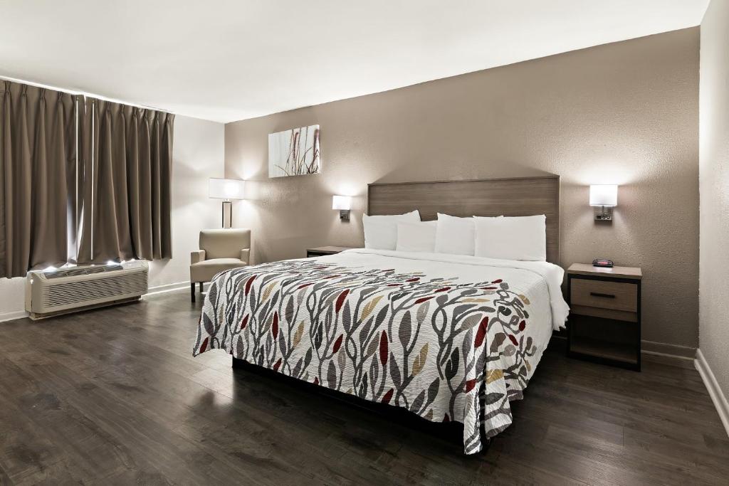 Habitación de hotel con cama y silla en Red Roof Inn & Suites Monroe, NC, en Monroe